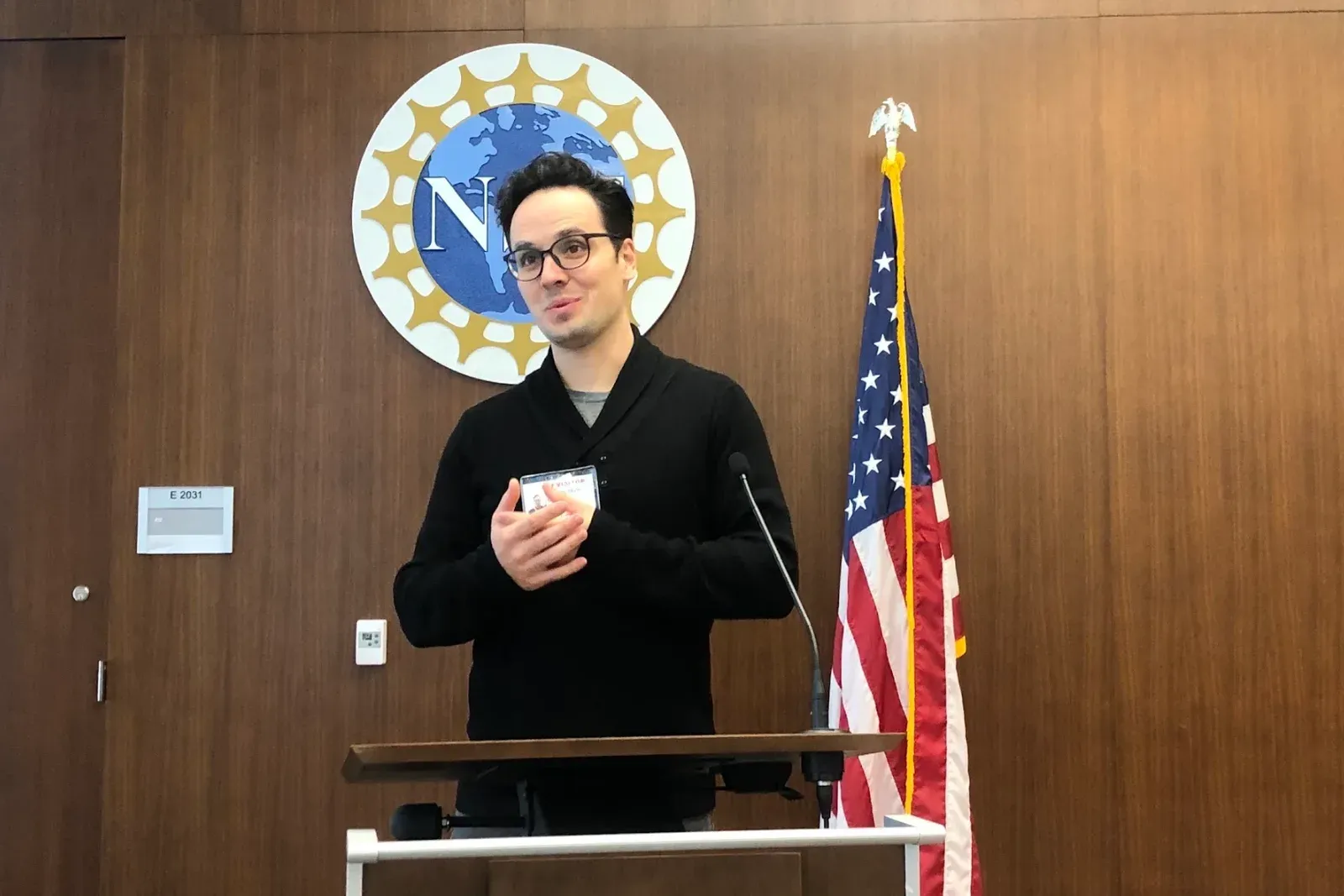 A speaker at an NSF briefing, at the podium under the National Science Foundation seal, beside the American flag.