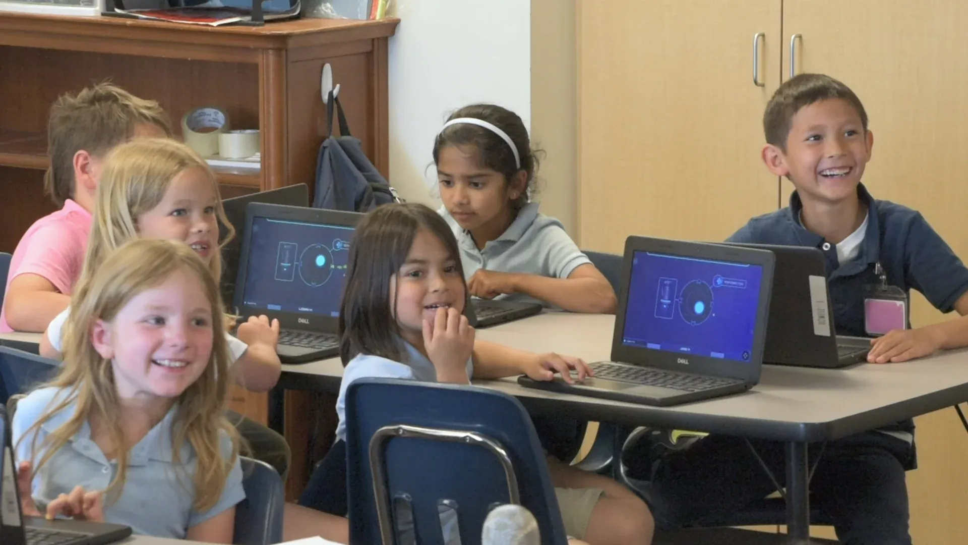 A row of young students beams up at the wall screen during a Mission, one boy laughing.